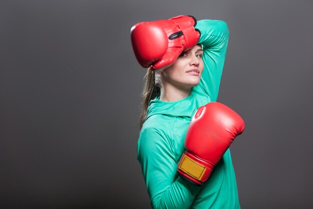 Mujer de boxeo en ropa deportiva verde y guantes de boxeo rojos