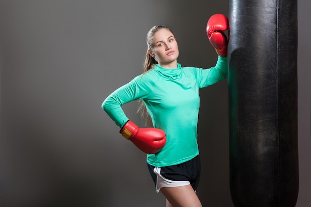 Mujer de boxeo en ropa deportiva verde y guantes de boxeo rojos