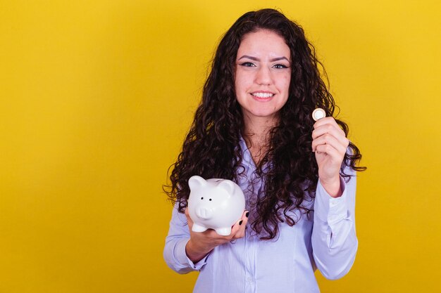 Mujer brasileña caucásica sosteniendo moneda y alcancía concepto de economía financiera ahorro