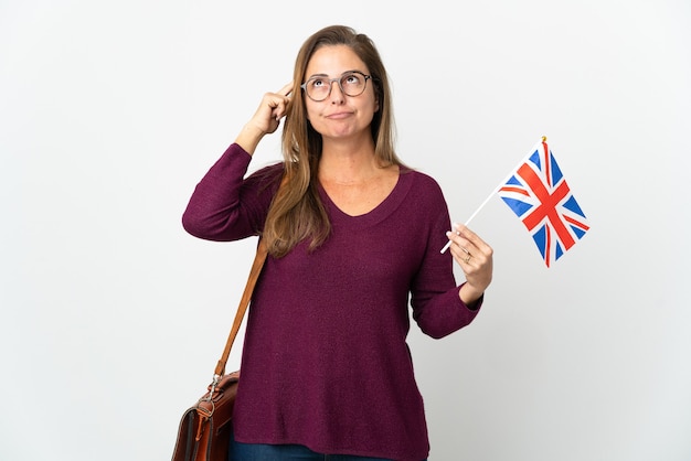 Mujer brasileña de mediana edad sosteniendo una bandera del Reino Unido aislada en blanco con dudas y pensamiento