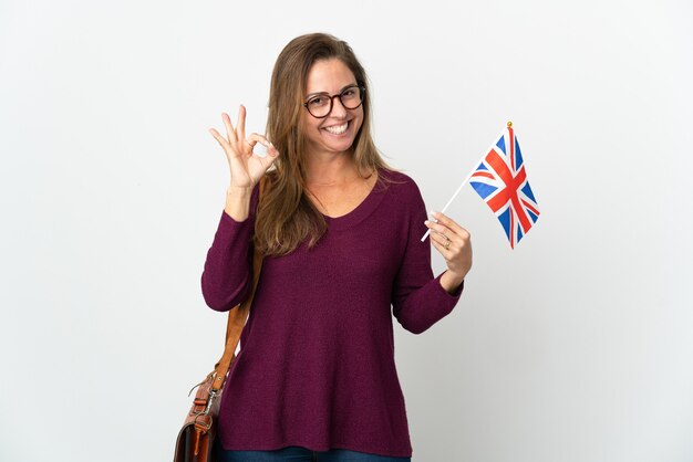 Mujer brasileña de mediana edad sosteniendo una bandera del Reino Unido aislado en blanco mostrando ok firmar con los dedos