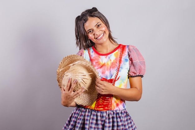 Mujer brasileña con ropa de campo Sao Joao party Junina party saludo sombrero en el pecho