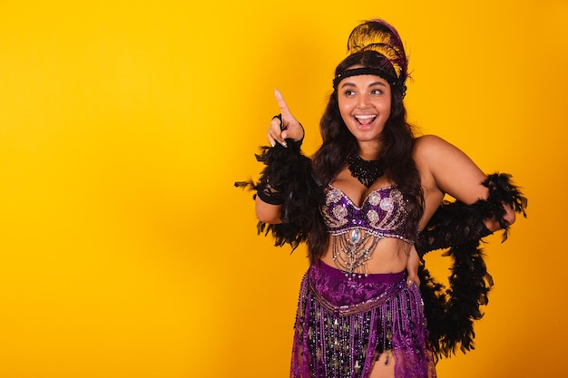 Foto mujer brasileña con ropa de carnaval apuntando a algo en la distancia
