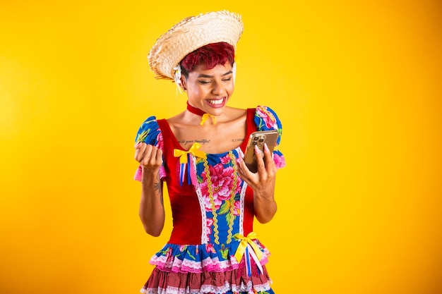 Mujer brasileña con ropa de festa junina Arraial Fiesta de San Juan con smartphone