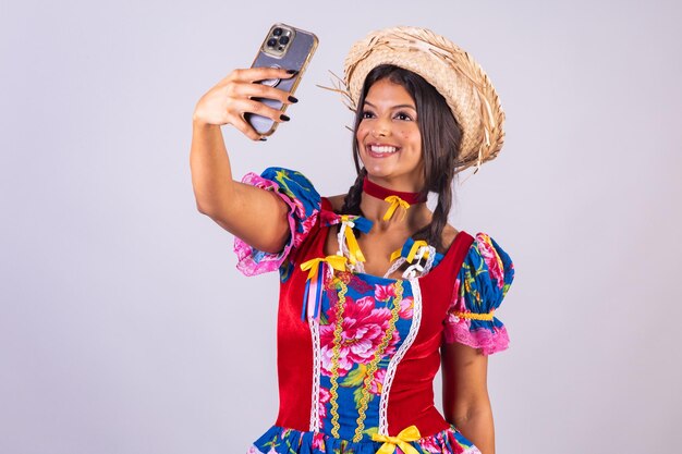 Mujer brasileña con ropa de festa de sao joao festa junina Con smartphone