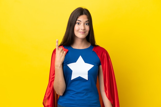 Foto mujer brasileña de superhéroe aislada sobre fondo amarillo apuntando con el dedo índice una gran idea