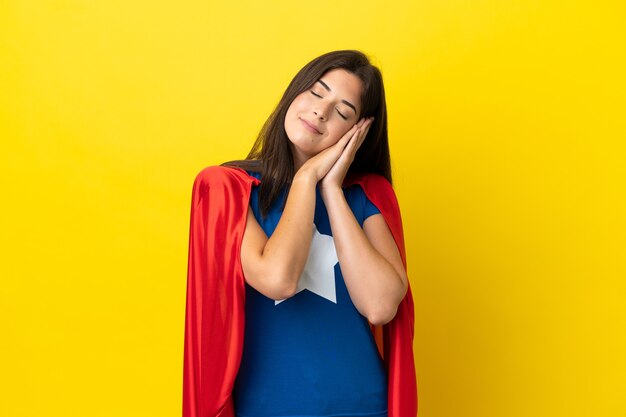 Mujer brasileña de superhéroe aislada sobre fondo amarillo haciendo gesto de sueño en expresión adorable