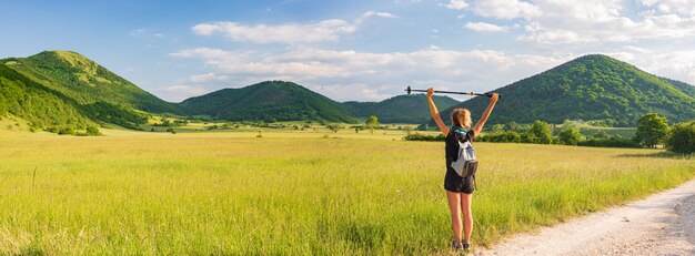 Mujer con los brazos extendidos mirando las vistas de un parque natural