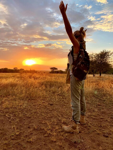 Foto mujer con los brazos extendidos de pie contra el cielo durante la puesta de sol