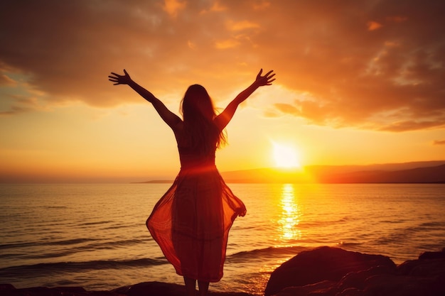 una mujer con los brazos extendidos en la playa al atardecer