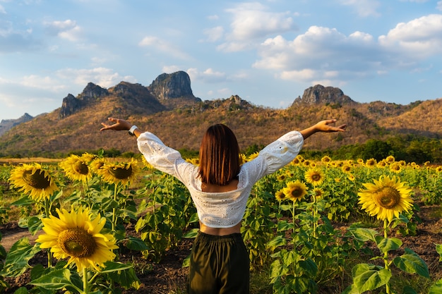 Mujer con los brazos levantados en el campo de girasol en Kao Jeen Lae en Lopburi, Tailandia