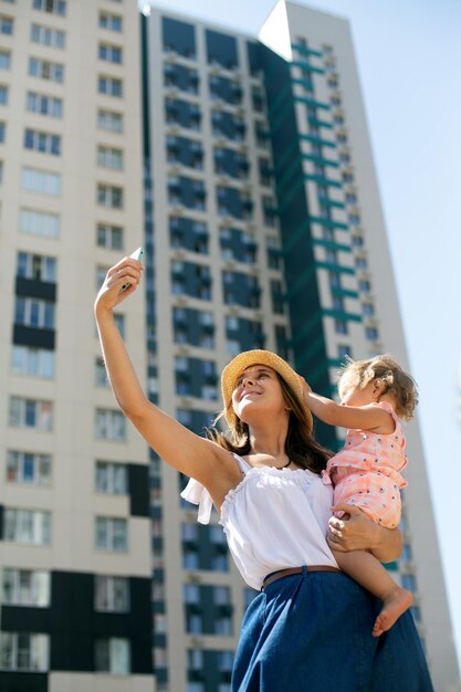 Foto mujer con los brazos levantados de pie contra edificios en la ciudad