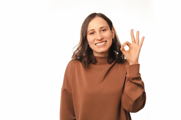 Mujer brillante sonriente muestra un gesto correcto para su trabajo o idea a la cámara