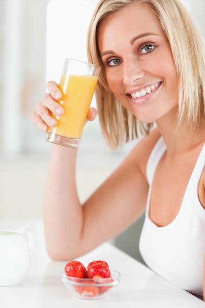 Foto mujer brindando con un vaso de jugo de naranja