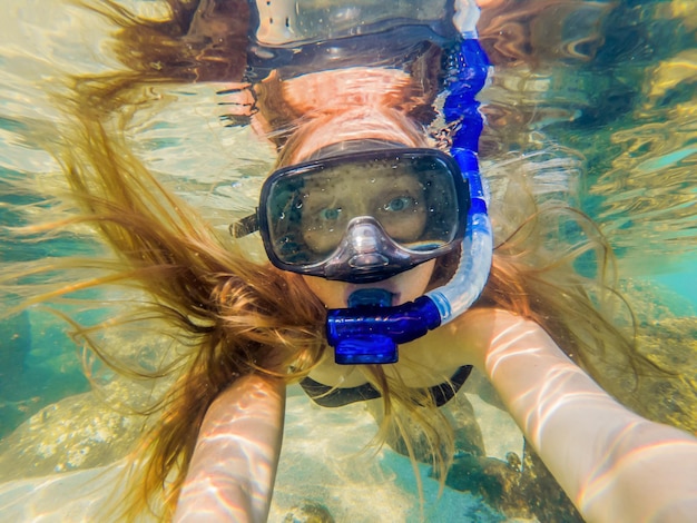 Mujer buceando en aguas tropicales frente a isla exótica