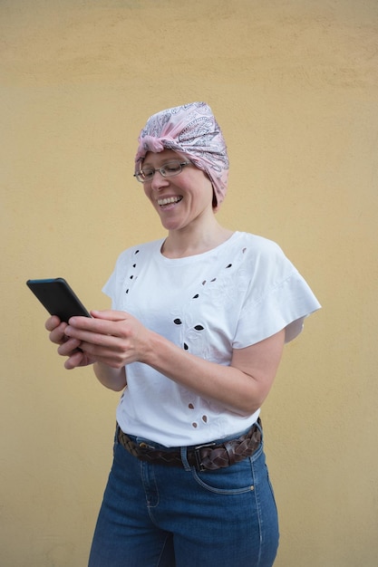Foto mujer con bufanda rosa sonríe mientras habla por teléfono inteligente