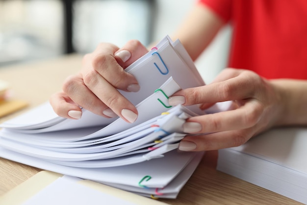 La mujer busca los materiales contables necesarios volteando documentos grapados la secretaria se sienta