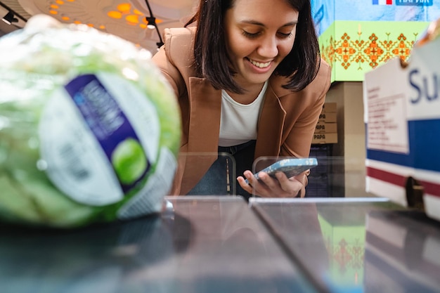 Mujer en busca de vegetales Tomando productos del estante Pareja de clientes de compras con lista de verificación