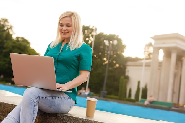 mujer buscando trabajo con una laptop en un parque urbano en verano