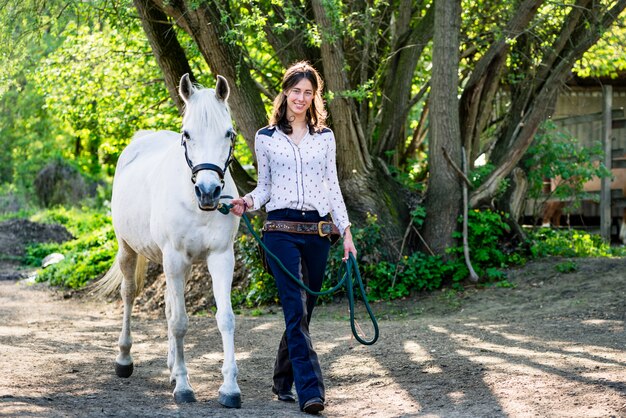 Mujer con caballo blanco caminando