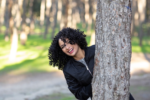 Mujer con cabello afro, en el bosque divirtiéndose feliz