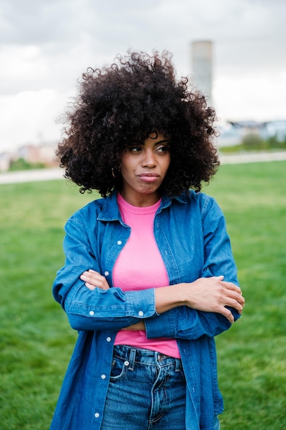 Mujer con cabello afro rizado que parece disgustada al aire libre en un estilo de vida de parque