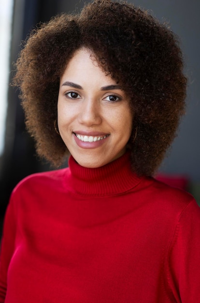 Una mujer con cabello afro sonríe a la cámara.