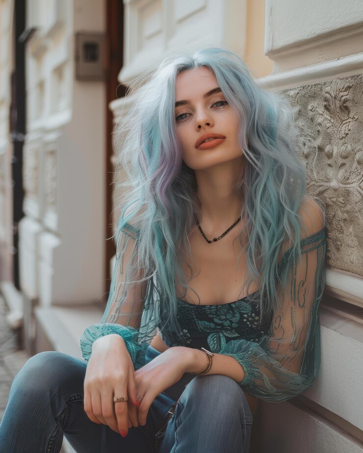 una mujer con cabello azul y una camisa verde se sienta en una repisa