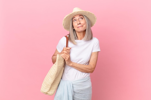 Mujer de cabello blanco de mediana edad encogiéndose de hombros, sintiéndose confusa e insegura. concepto de verano