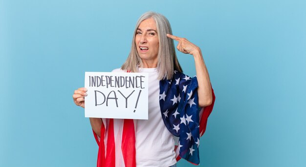 Mujer de cabello blanco de mediana edad que se siente confundida y perpleja, mostrando que estás loco. concepto del día de la independencia