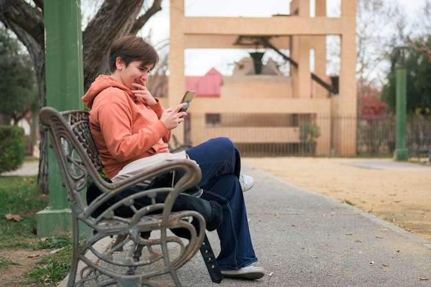 Mujer con cabello corto mirando su teléfono móvil en un parque