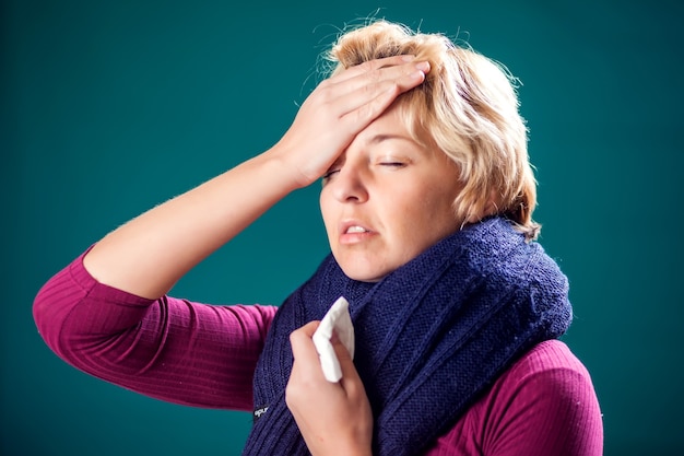 Una mujer con cabello corto y rubio contrajo gripe y tiene dolor de cabeza. Concepto de personas, salud y medicina