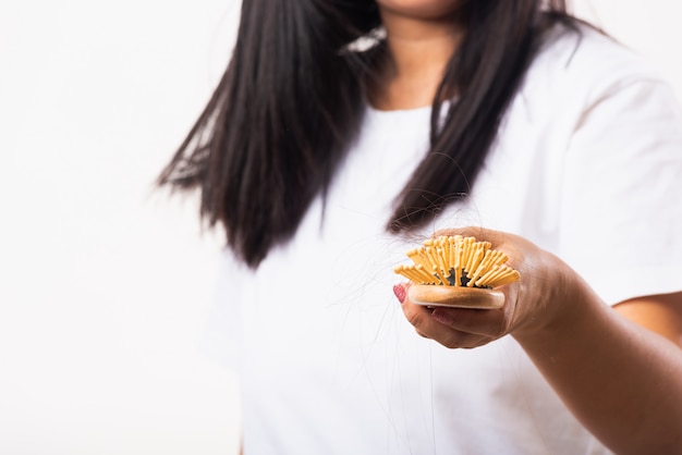 Mujer con cabello débil, muestra un cepillo para el cabello con cabello dañado de larga pérdida en el cepillo de peine en la mano