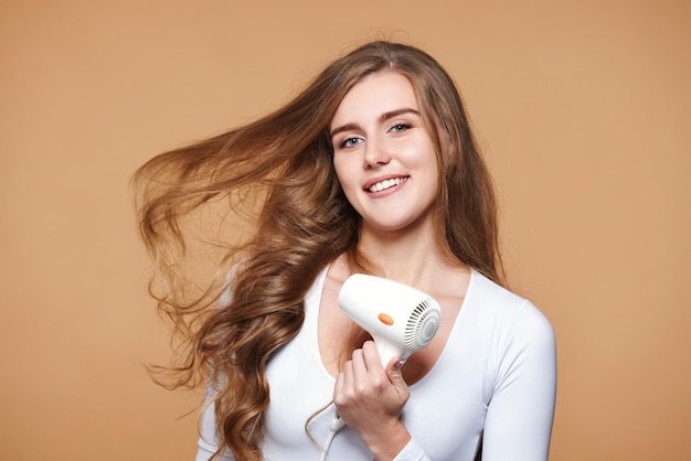 Mujer con cabello fuerte y saludable usando secador de pelo