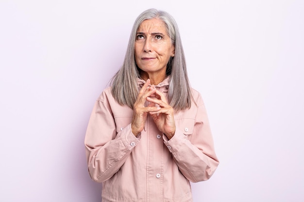 Mujer de cabello gris de mediana edad intrigando y conspirando, pensando en trucos y trampas tortuosos, astuta y traicionando