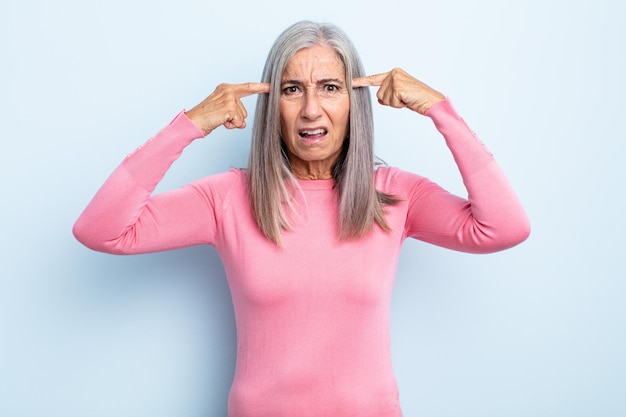 Mujer de cabello gris de mediana edad con una mirada seria y concentrada, haciendo una lluvia de ideas y pensando en un problema desafiante