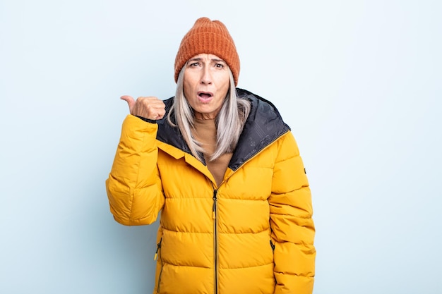 Mujer de cabello gris de mediana edad mirando asombrado con incredulidad. concepto de clima frío