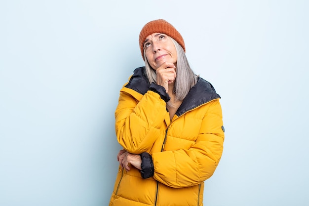 Mujer de cabello gris de mediana edad pensando, sintiéndose dudoso y confundido. concepto de clima frío