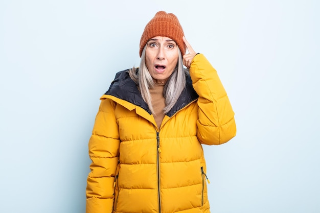 Mujer de cabello gris de mediana edad que parece sorprendida, dándose cuenta de un nuevo pensamiento, idea o concepto. concepto de clima frío