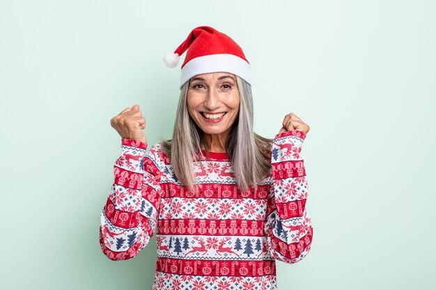 Mujer de cabello gris de mediana edad que se siente conmocionada, riendo y celebrando el éxito. concepto de navidad