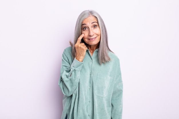 Mujer de cabello gris de mediana edad que te vigila, no confía, mira y permanece alerta y vigilante