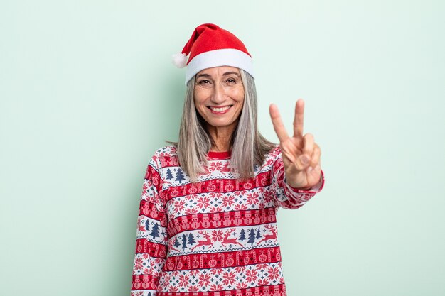 Mujer de cabello gris de mediana edad sonriendo y mirando amigable, mostrando el número dos. concepto de navidad