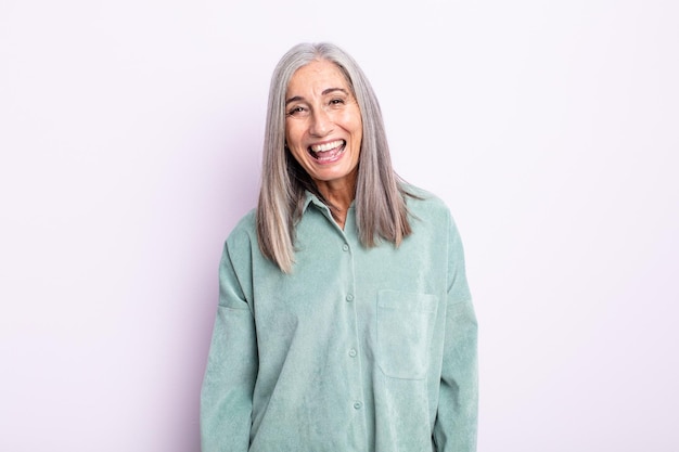 Mujer de cabello gris de mediana edad con una sonrisa grande, amable y despreocupada, con un aspecto positivo, relajado y feliz, escalofriante