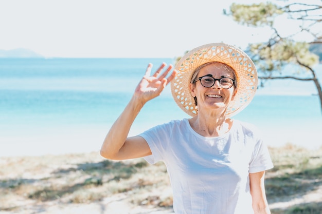 Mujer con cabello gris en la playa durante un día súper soleado concepto de libertad senior copia espacio sol