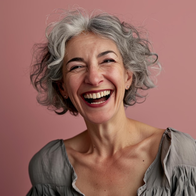 Una mujer con cabello gris riendo y sonriendo.