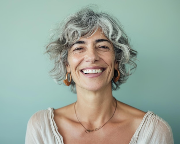 Foto una mujer con cabello gris sonriendo y mirando a la cámara.