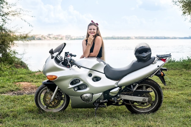 Mujer con cabello largo posando junto a la motocicleta