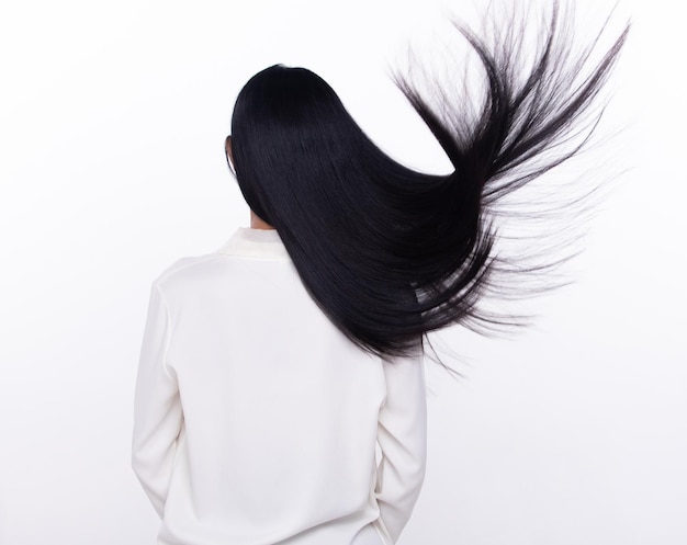 La mujer de cabello negro largo y recto negro lanza una mosca en el aire con alegría elegante y divertida de la moda.