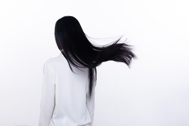 La mujer de cabello negro largo y recto negro lanza una mosca en el aire con alegría elegante y divertida de la moda.