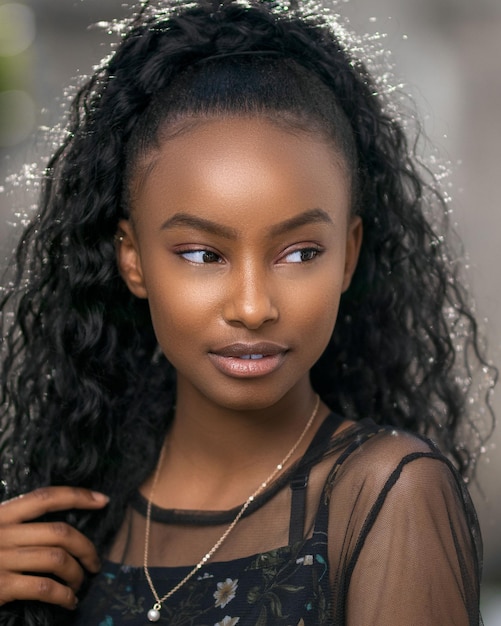 Una mujer con cabello negro y un top negro con un brillo plateado en la cara.